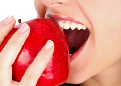 Kraftvoll in einen Apfel beissen nach Einsatz eines Zahnimplantates