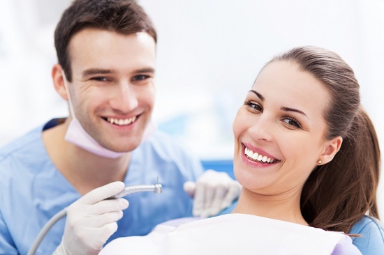 Junge Frau freut sich mit ihrem Zahnarzt nach einer Kariesbehandlung