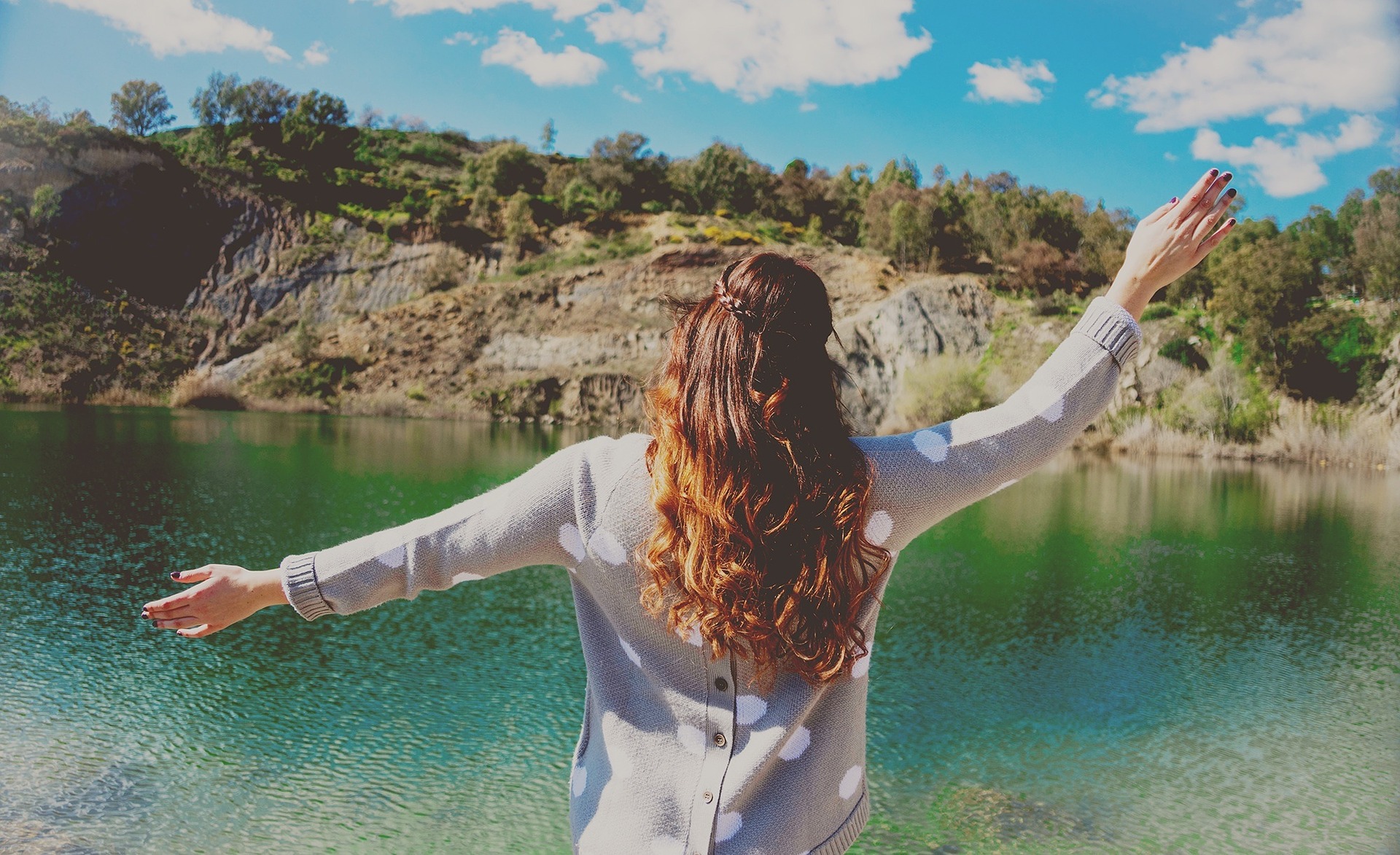 Girl standing on the shore of a clear lake