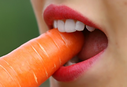 Eine leckere frische Karotte essen nach einer professionellen Mundhygiene